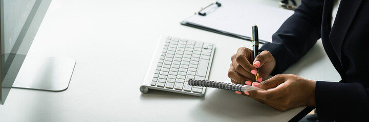 African american woman in headset writing notes while talking support customer in call center