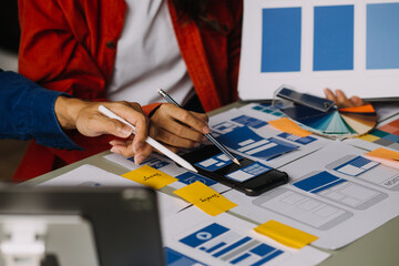 Close up ux developer and ui designer brainstorming about mobile app interface wireframe design on...