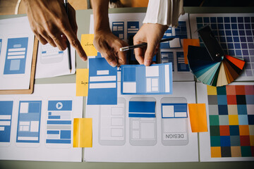 Close up ux developer and ui designer brainstorming about mobile app interface wireframe design on...