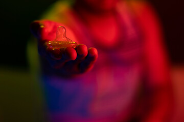Young man offering condom. Safe sex. Hot colors, red and yellow. Ballad or party. With blurred...