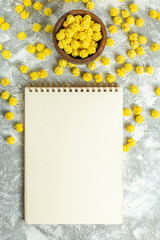 top view lttle yellow candies with notepad on white background color sweet candy tea