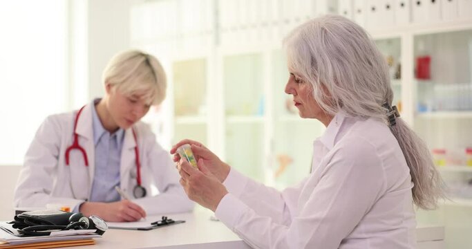 Therapist gives jar of medicine to elderly woman patient in clinic. Cardio pills for sick people