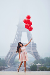 Woman with bunch of red balloons near the Eiffel tower in Paris