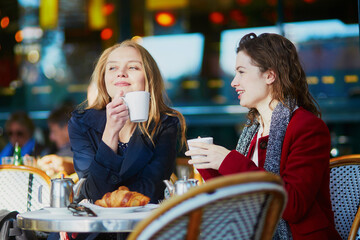 Two young girls in Parisian outdoor cafe - obrazy, fototapety, plakaty