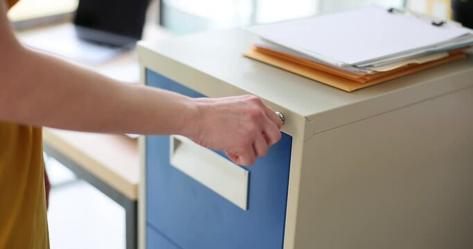 Woman hand opens metal box in office with key. Safety of business documents