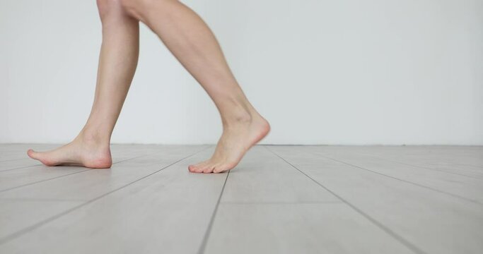 Closeup of beautiful female legs with perfectly smooth skin. Woman walks at home and enjoys the morning and relaxes