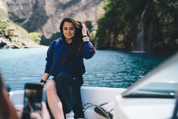 Smiling young mixed race woman sitting on side of boat