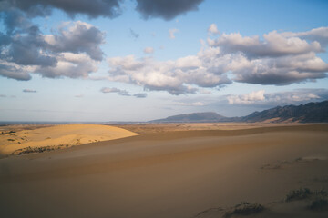 Fototapeta na wymiar Desert with mountains on one end under cloudy sky