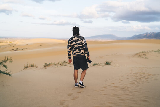 Unrecognizable traveler standing on sandy desert valley