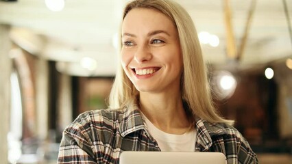 Portrait of charming inspired blond woman freelancer in casual clothes hold laptop and looking ahead at coworking workplace Confident young trainee pensive thinking about future career indoors