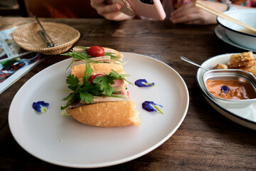 Close-up of Vietnamese Sandwich on Table and Woman taking a photo