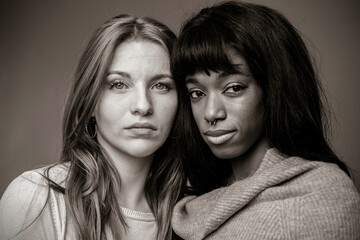 Couple of young women of different ethnicities - Caucasian woman with African female partner pose looking at camera - Multiculturalism and multiethnic concept - Black and white editing