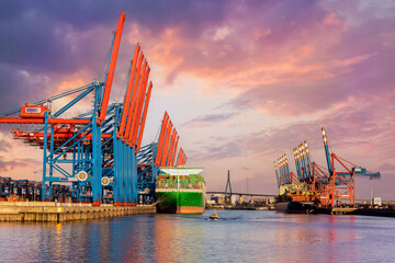 Scenic front giant cargo container ship loading Hamburg city port harbour seaport cranes warm dramatic sky evening sunset light. Global commercial trade freight charter shipping logistics background - obrazy, fototapety, plakaty
