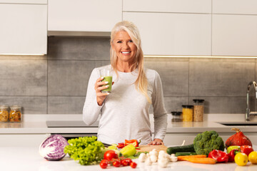 Beautiful, older woman making a healthy green - fruit and vegetable smoothie.