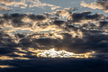 Naklejka na ściany i meble Sky replacement sun rays peeking through dark dramatic orange and gray clouds