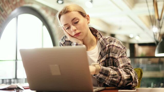 Tired exhausted young blond woman freelancer sleeping dozing on coworking workplace at working time Portrait of overworked self employee worker falling asleep on desktop next to computer indoors