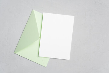 Blank invitation card mockup with light green envelope on grey
