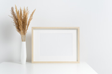 Blank picture frame mockup with botanical decoration in white minimalistic room interior