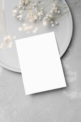 Blank wedding invitation card mockup with dry gypsophila flowers decor on grey concrete background