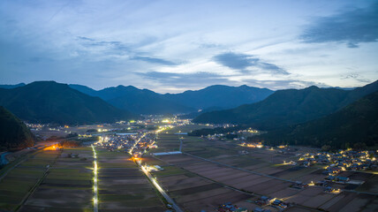 Lights from roads and homes by rice fields and mountains in blue hour