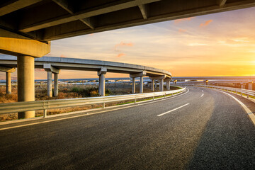 Asphalt highway and bridge with sky clouds at sunset