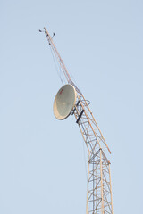 The communication tower is damaged by a storm with a blue cloudy background.