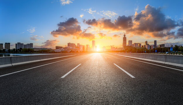Straight asphalt road and city skyline with buildings scenery