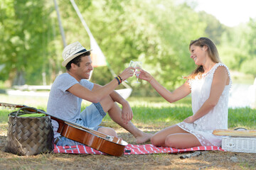 young couple in the park cheering during picnic