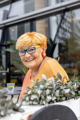 Portrait of a mature 80 years old smiling woman in glasses looking in camera