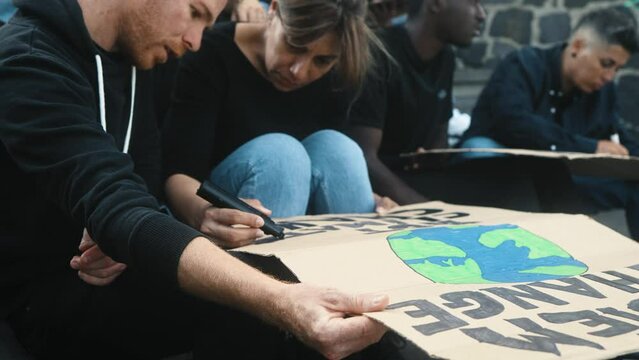Multiracial activists designing protest banners against climate change - Global warming concept