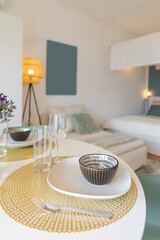 Detail of a place set for lunch, with a plate, cutlery and a glass. There is a bouquet of fresh flowers