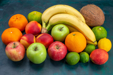 front view different fruit composition bananas tangerines apples on dark-blue desk fruit fresh mellow ripe color vitamine