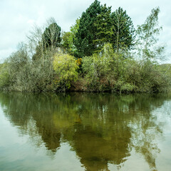 Fototapeta premium Fishing Lake Surrounded By Trees Reflected In The Calm Water