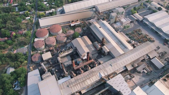Sugar processing biomass factory with pollution smoke from chimney and tank warehouse during sugarcane harvesting season