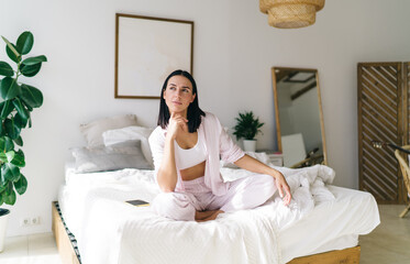 Thoughtful woman sitting in bed after awakening