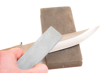 knife sharpening, knife on isolated white background with abrasive stone. the concept of the work of a knife sharpening master