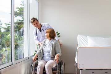 caucasian man doctor is examining the female older patient in wheelchair the hospital.