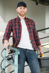 busy handyman carrying toolbox and descending staircase