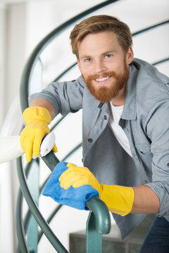 young handsome man in yellow gloves cleaning stairs
