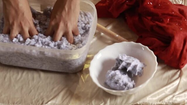 Hands mixing and squeezing excess water from paper mache mixture, sustainable zero waste lifestyle
