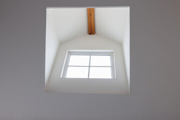 Dormer wooden window in the white sloping ceiling. garret house window. window interior design.