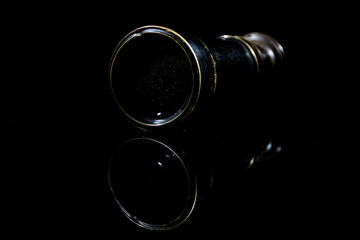 small vintage mono ocular spyglass on black surface with black background