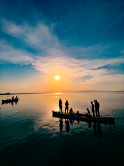 Silhouette Group of People on boat in sea With beautiful sky during Sunset