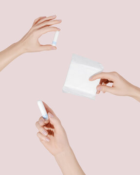 Female hands holding a sanitary pad and tampons for menstruation. Concept: female's hygienic product for period's day. Woman healthcare. Monthly intimate hygiene.