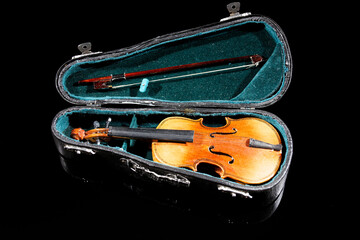 small model of an old violin with bag on black surface with black background