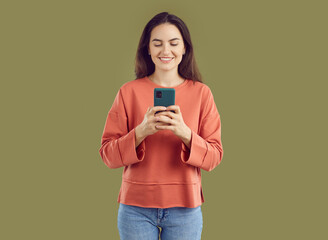 Smiling brunette young woman taking photo on smartphone. Attractive positive girl in casual clothes taking picture with mobile phone. Optimistic woman using phone for photographing or communication