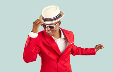 Time for party. Happy refined and stylish african man having fun dancing on pastel light blue...