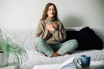Relaxation techniques: Woman practicing pranayama in lotus position on bed, breathing exercises to reduce stress and anxiety, achieving inner balance and harmony, mindfulness and meditation practice - obrazy, fototapety, plakaty