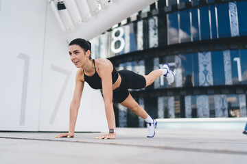 Fototapeta premium Positive sportswoman training on street in city district