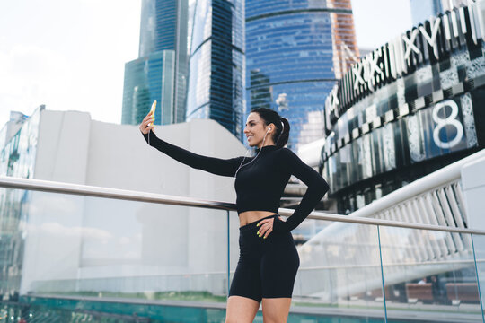 Sportswoman making selfie on smartphone near glass railing